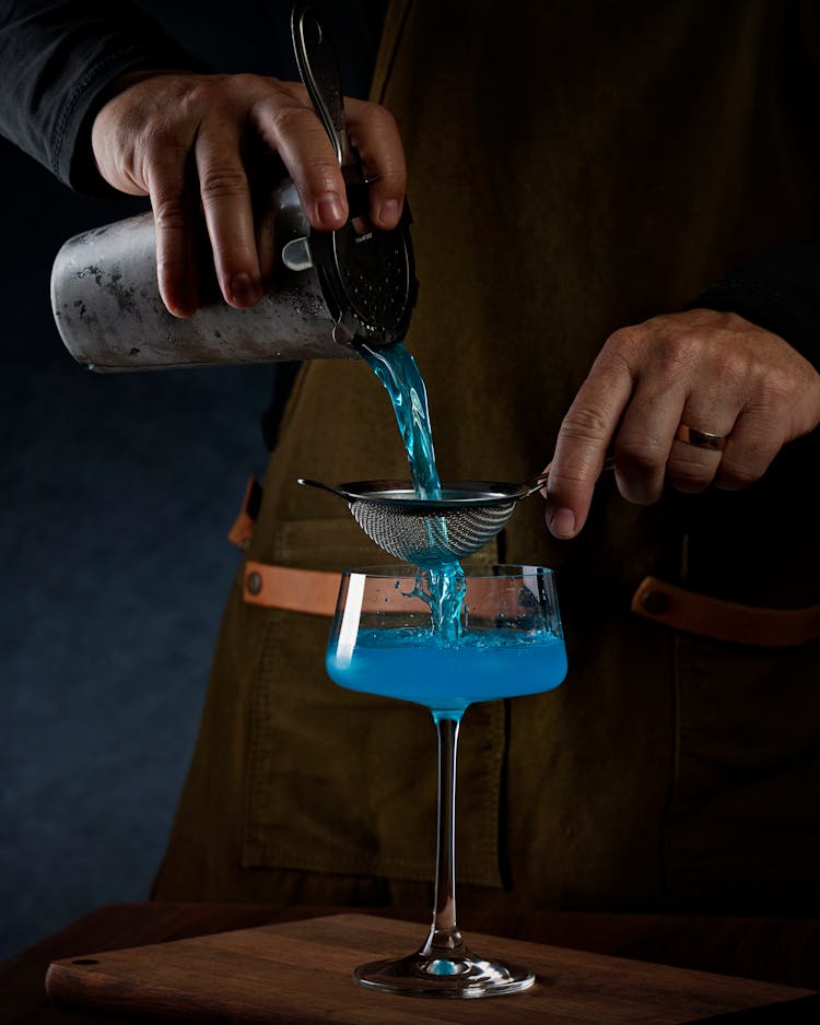 Hands Pouring Cocktail Through Sieve