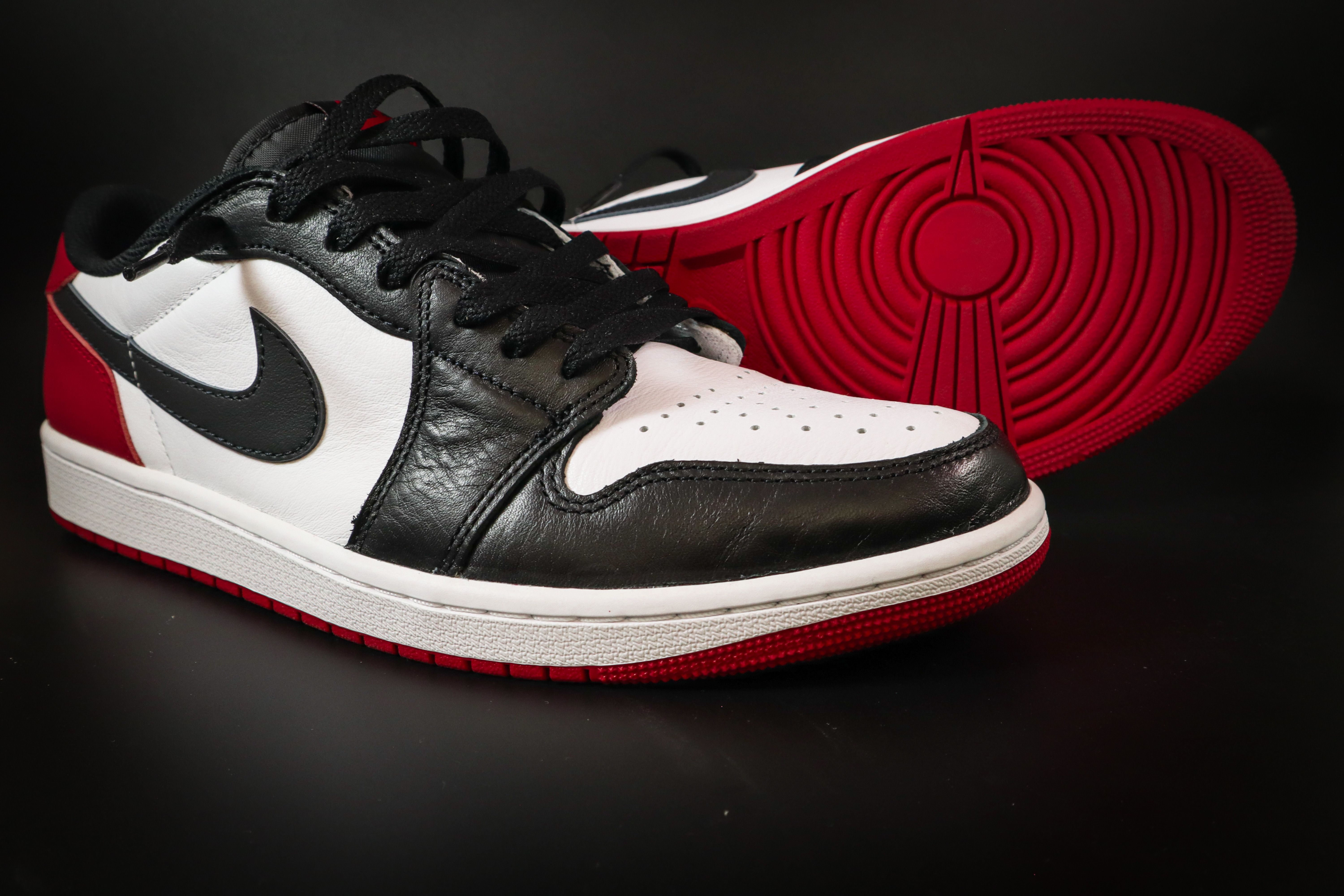 Detailed close-up of black, white, and red sneakers on black background.