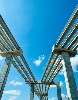 Low-angle view of a modern concrete bridge under construction with a clear blue sky backdrop, ideal for engineering themes.