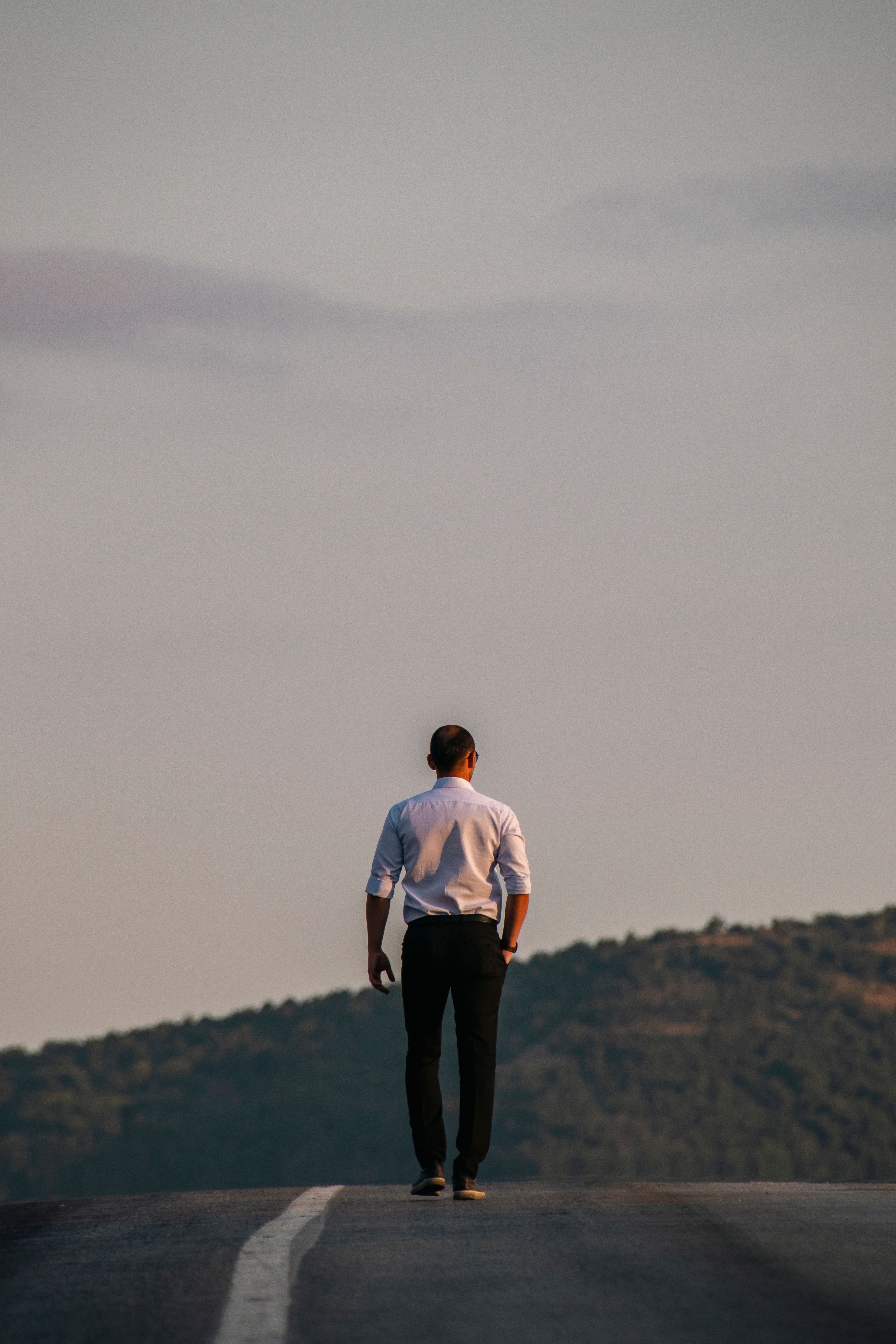 Back View of an Elegant Man Walking on an Asphalt Road · Free Stock Photo