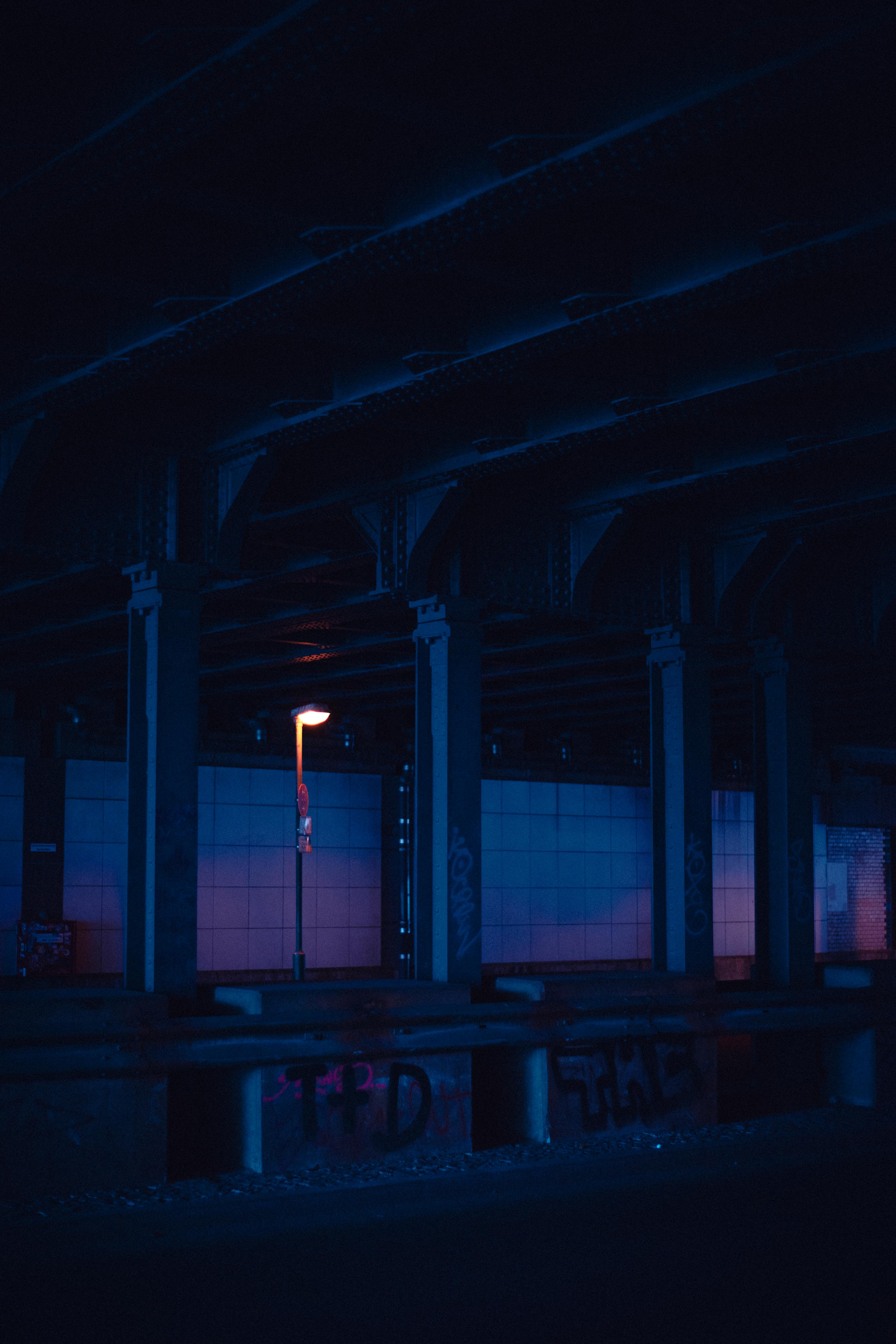 Eerie nighttime view under a city overpass with minimal light, creating a moody atmosphere.