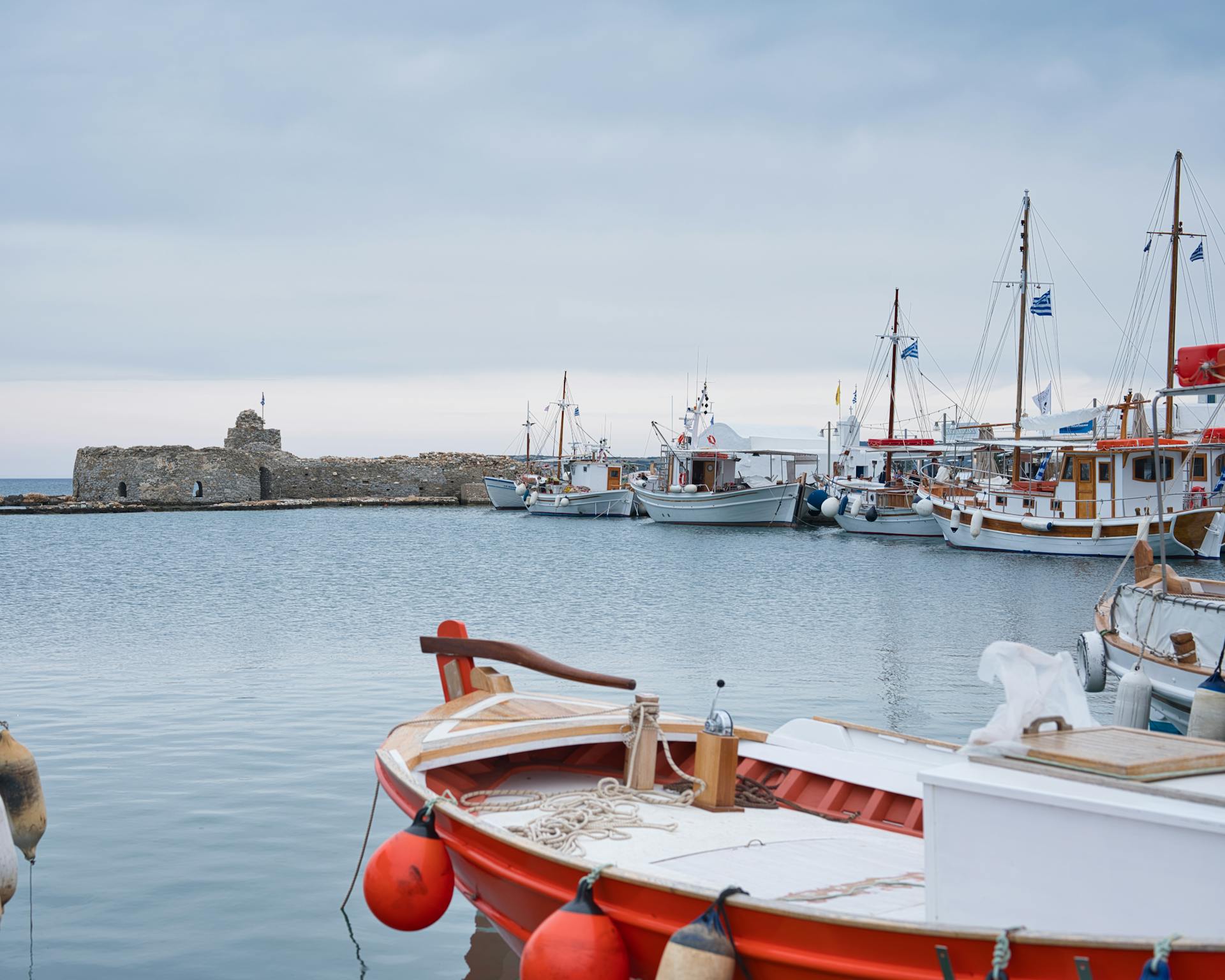 Peaceful harbor scene with moored boats in Naousa, Greece against a calm sea backdrop.
