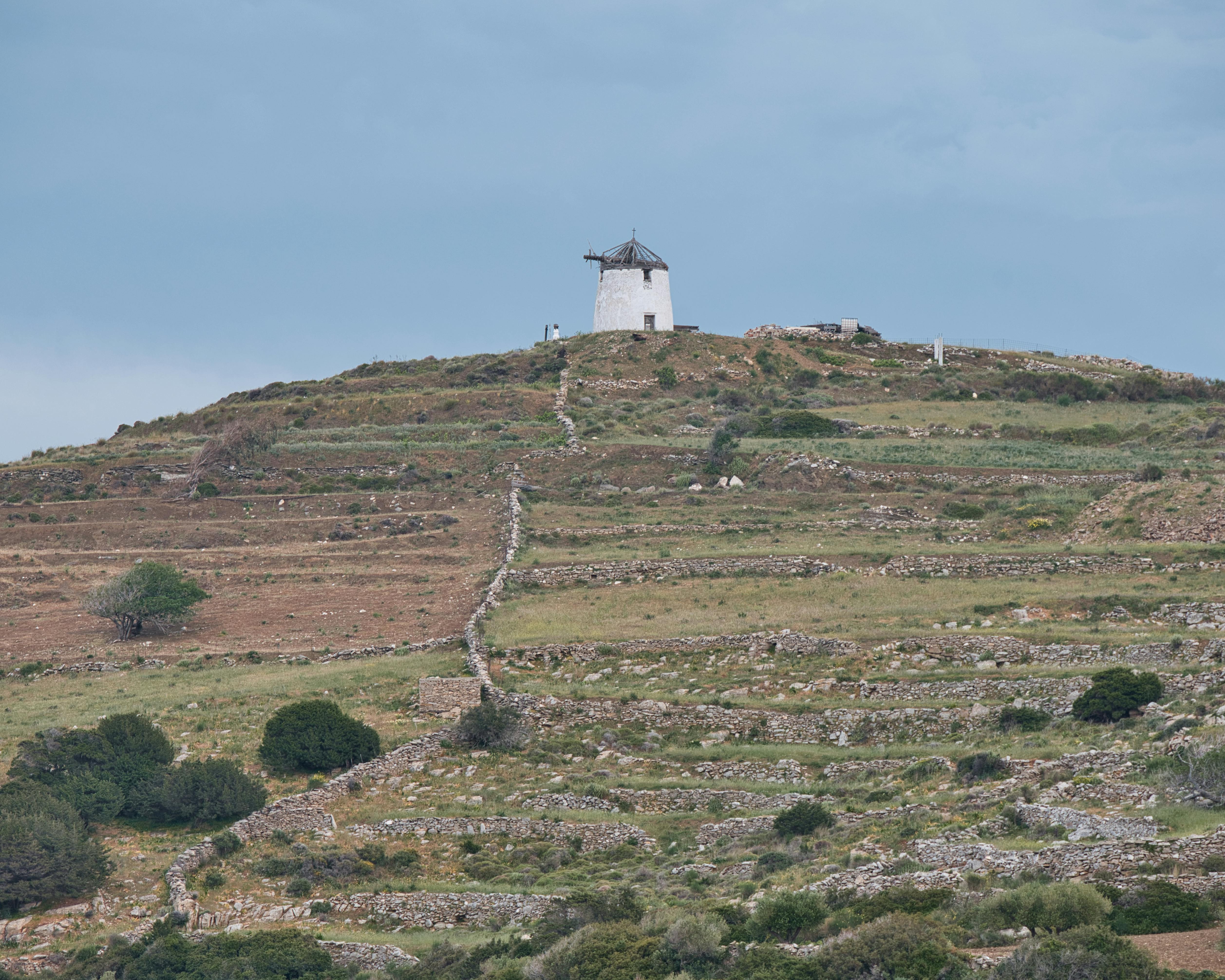 Traditional Greek windmill silhouetted against sunset sky in Paros