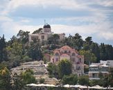 View of the National Observatory and an Orthodox church in Athens, Greece, surrounded by lush greenery.