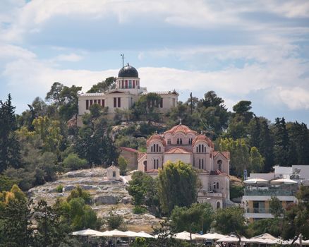 View of the National Observatory and an Orthodox church in Athens, Greece, surrounded by lush greenery.