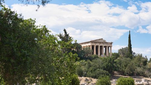 Free Temple of Hephaestus in Athens surrounded by greenery and blue sky. Stock Photo