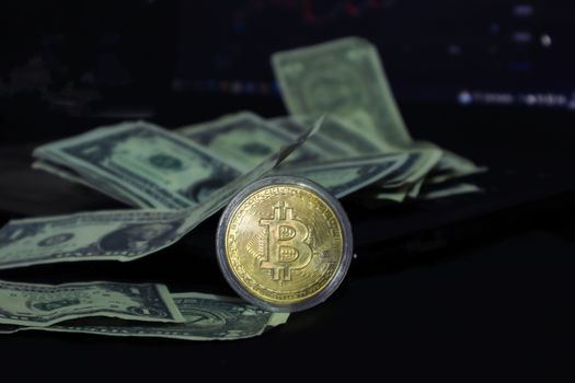 Bitcoin coin surrounded by scattered US dollar bills on a dark surface, symbolizing modern finance.