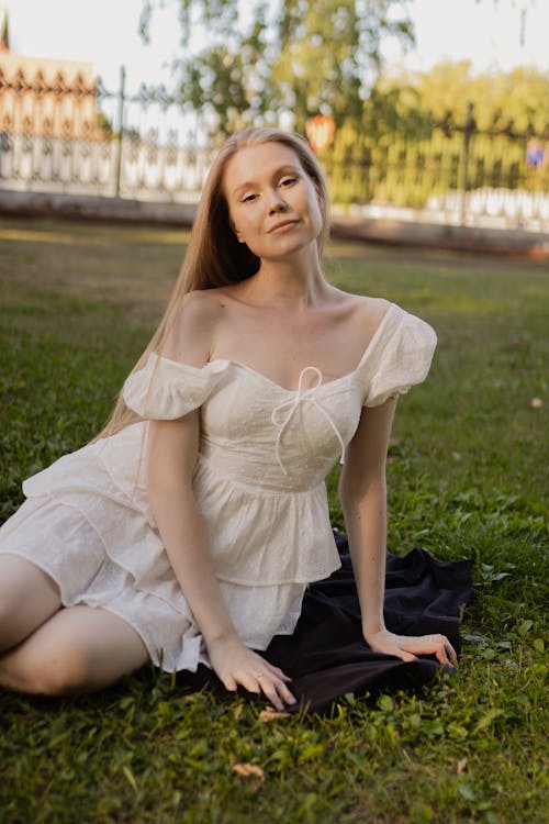 Blonde Woman Posing in White Ruffled Dress on a Lawn