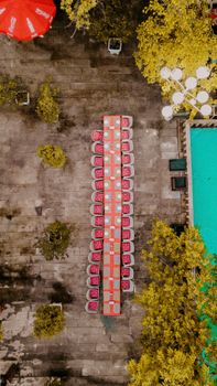 Long table setup for dining outdoors by a pool, captured from above.