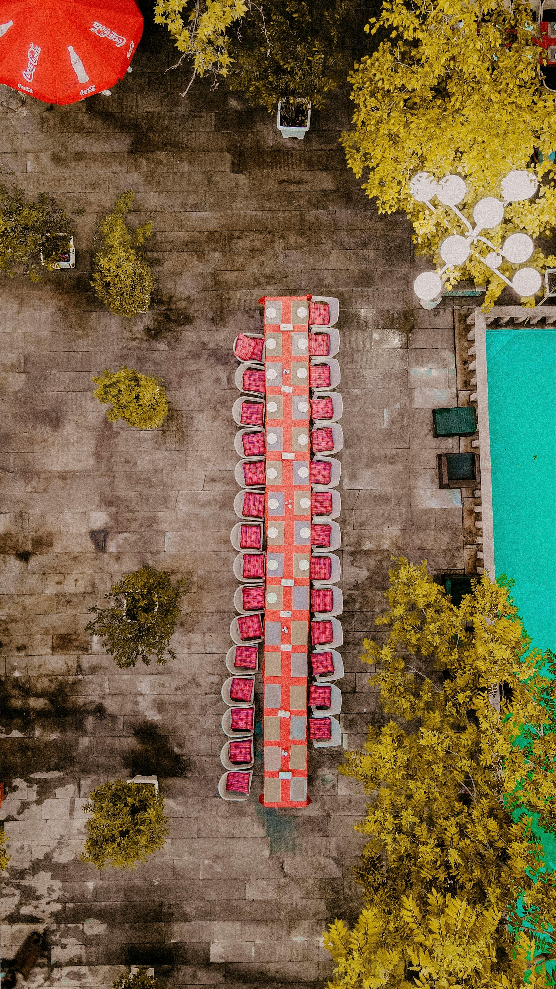 Free Long table setup for dining outdoors by a pool, captured from above. Stock Photo