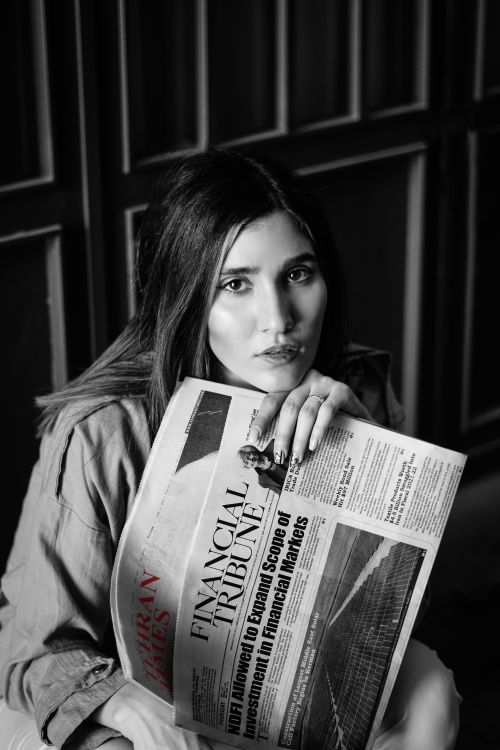 Free Elegant black and white portrait of a woman holding a financial newspaper indoors. Stock Photo
