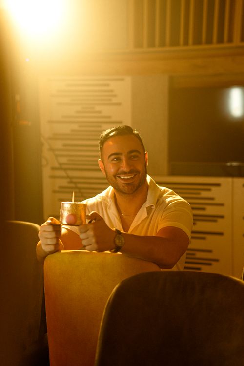 Free A smiling man holding a drink illuminated by warm lighting, creating a cozy atmosphere. Stock Photo