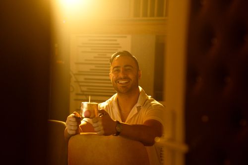 Free Smiling man with a drink in warm lighting, capturing a cozy and inviting mood. Stock Photo