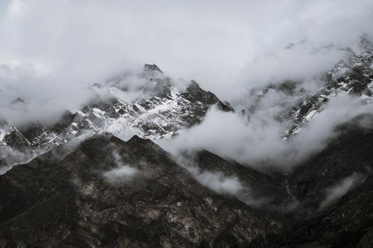 薄雾笼罩着崎岖的雪山，营造出神秘而宁静的景观