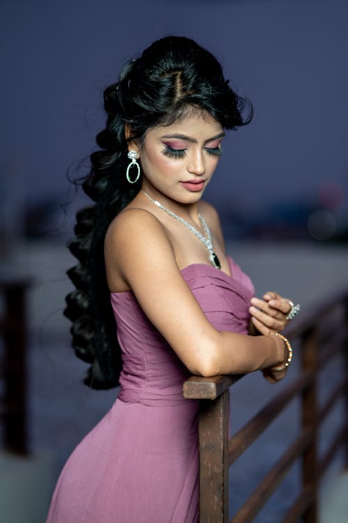 Brunette Wearing a Purple Dress and a Diamond Jewellery, Leaning against a Handrail