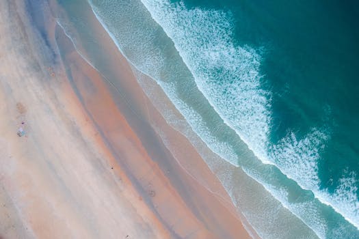 这张航拍照片令人惊叹，它捕捉了宁静的海滩，展现了轻柔波浪与沙质海岸相遇的景象