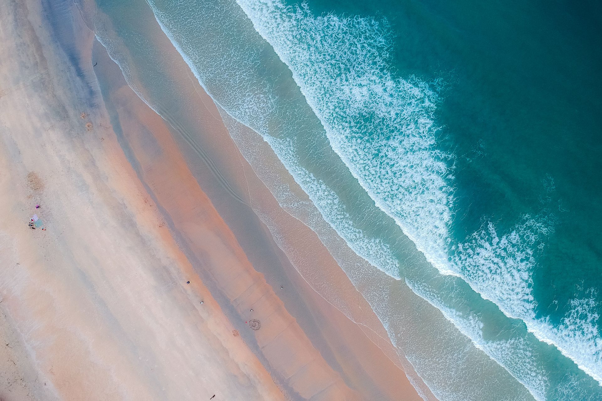 A breathtaking aerial shot of a serene beach showcasing gentle waves meeting sandy shores.