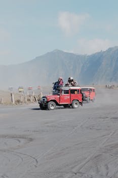 Jeeps driving through dusty terrain with a backdrop of Mount Bromo, perfect for adventure travel enthusiasts.