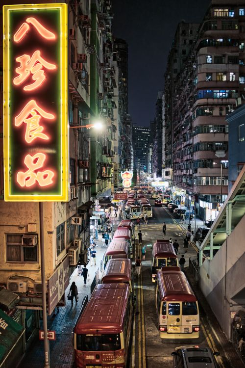 Free Bustling street scene in Hong Kong at night with neon signs and traffic. Stock Photo