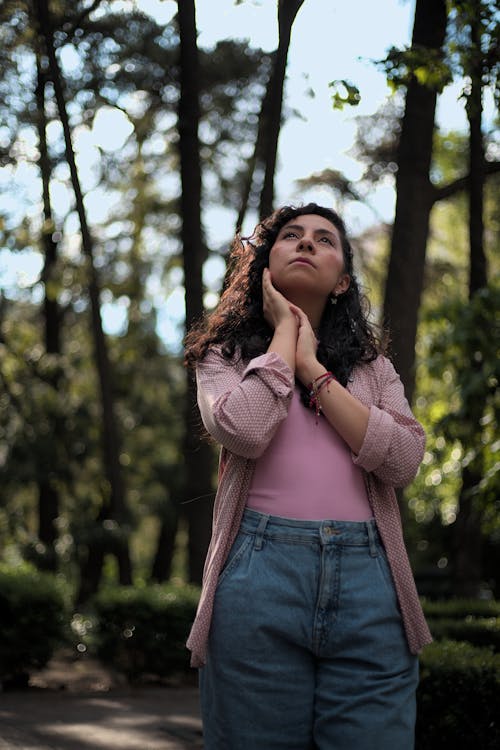 Young Woman Standing in the Park and Looking Up 