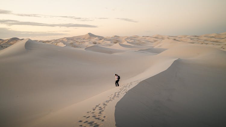 A Person Walking Across A Sand Dune