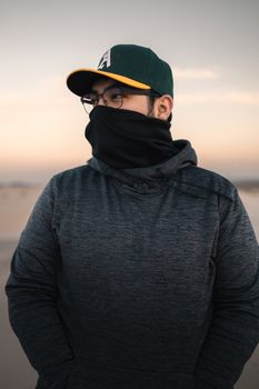 Portrait of a man in a baseball cap and hoodie on the Samalayuca Dunes during sunset with a serene backdrop.
