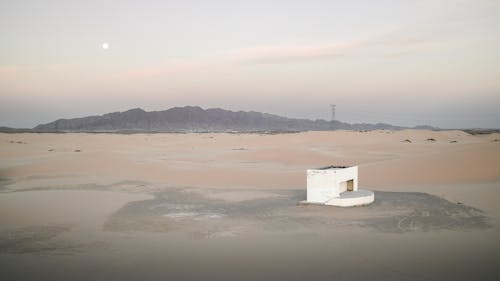 A white building in the desert with a mountain in the background