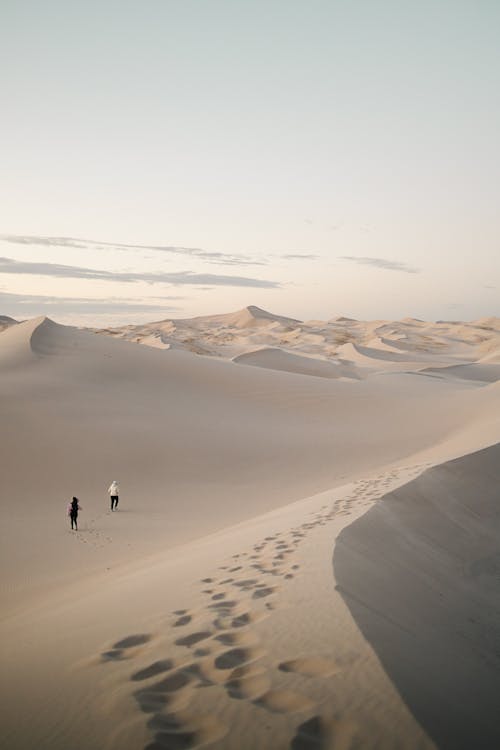 Two people walking through the sand dunes