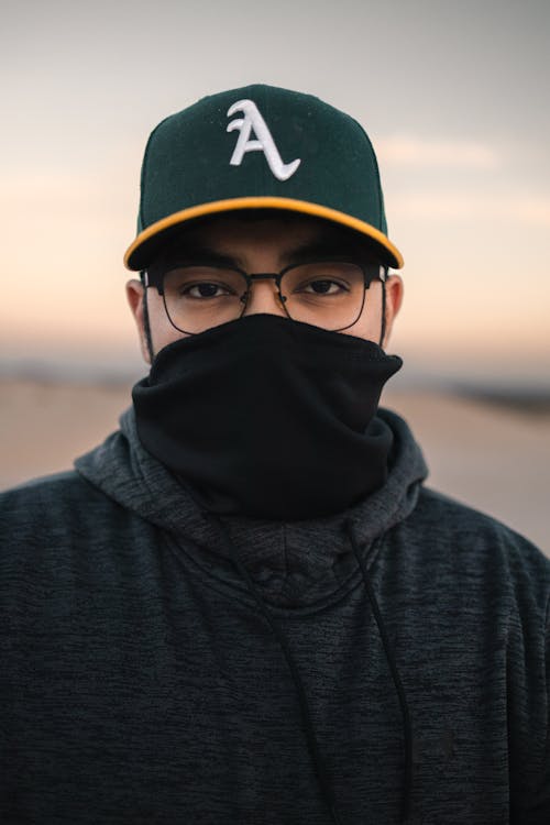 A man wearing a baseball cap and a face mask