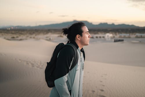 A man in a backpack standing in the desert