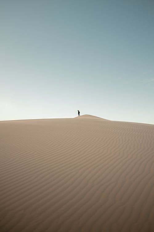 A lone person standing on top of a dune