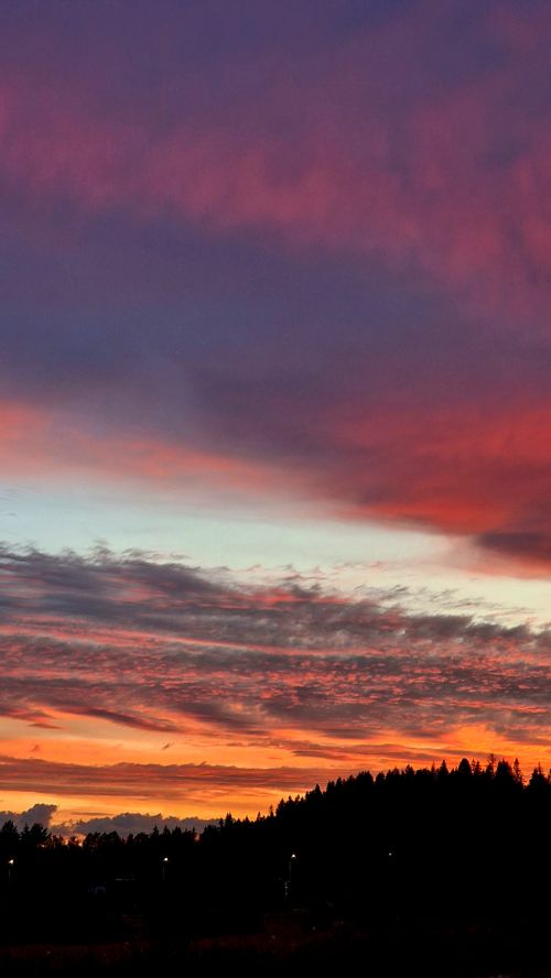 Free A breathtaking silhouette of hills against a vibrant sunset sky with brilliant colors. Stock Photo