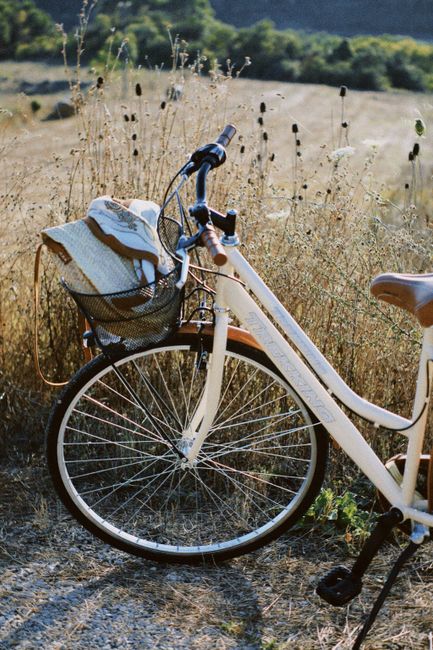 A charming bicycle with a straw hat in a peaceful rural field on a sunny day.