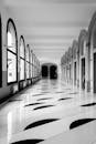 Black and White Photograph of a Corridor with a Marble Patterned Floor
