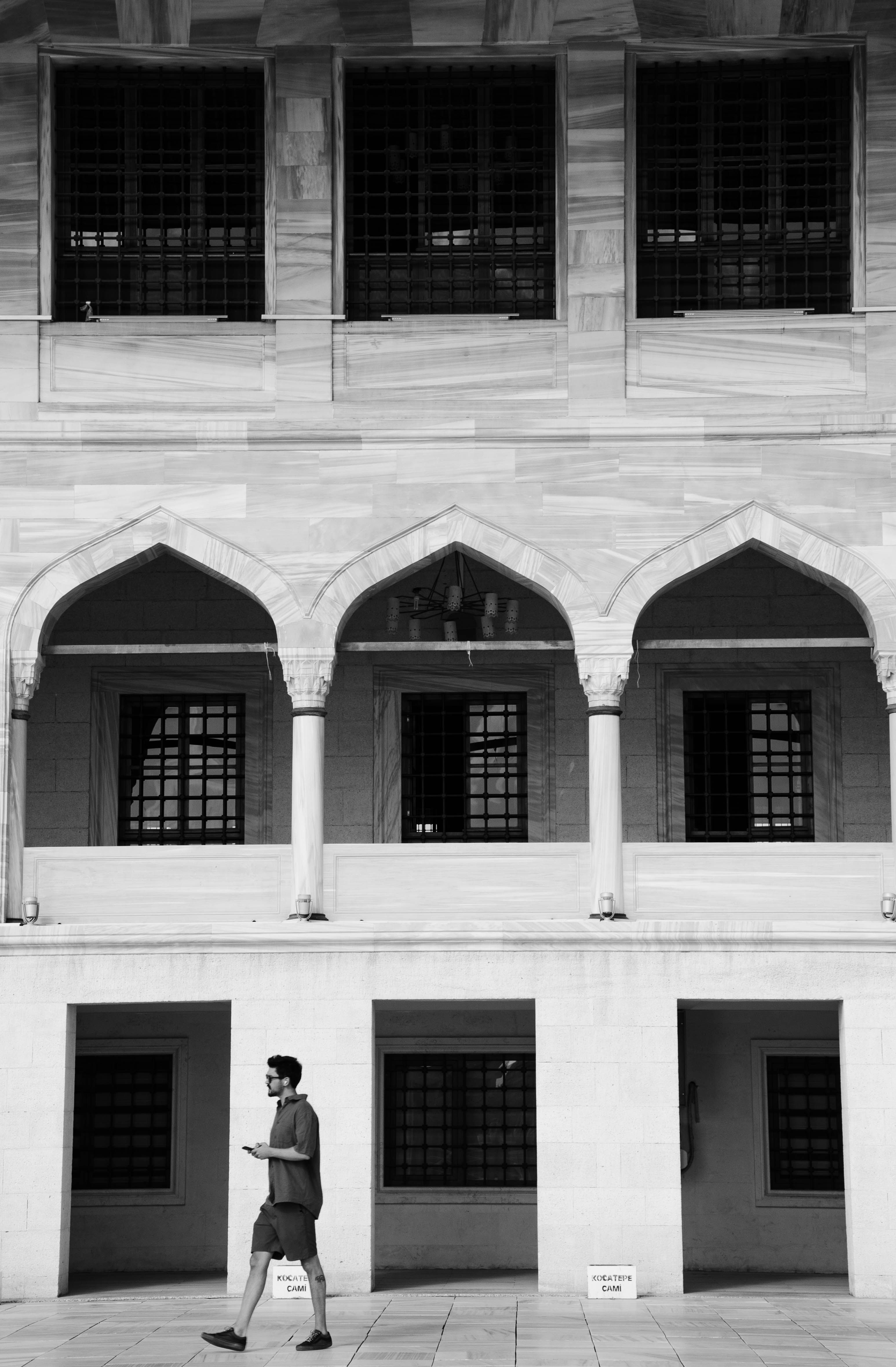 A man walks beside an architectural facade in Ankara, Türkiye, showcasing Ottoman design.