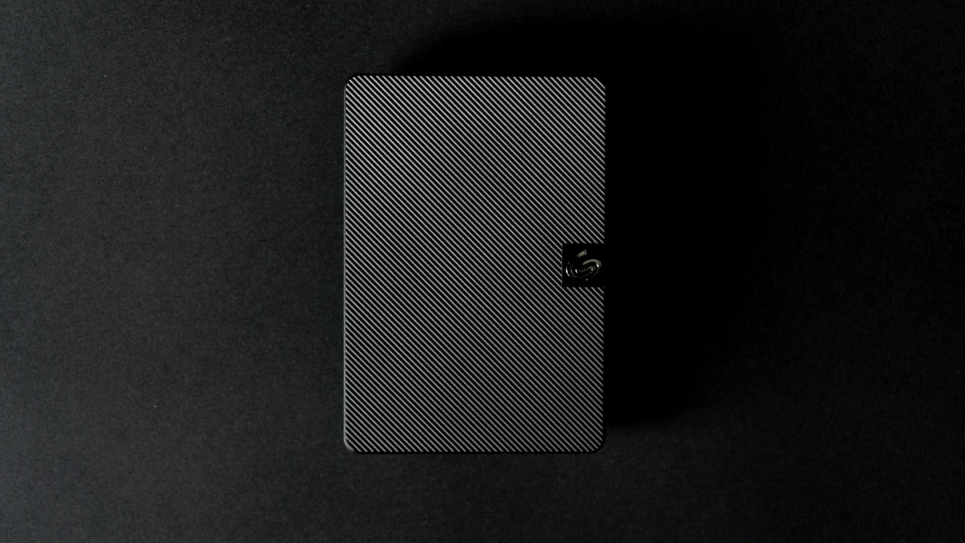 Close-up of a sleek external hard disk against a black backdrop, showcasing modern technology design.