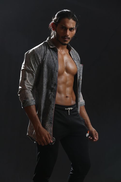 Free Confident muscular man posing in studio wearing an open shirt and joggers. Stock Photo