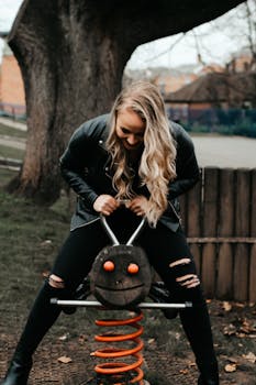 金发女子坐在户外游乐场的弹簧摇椅上