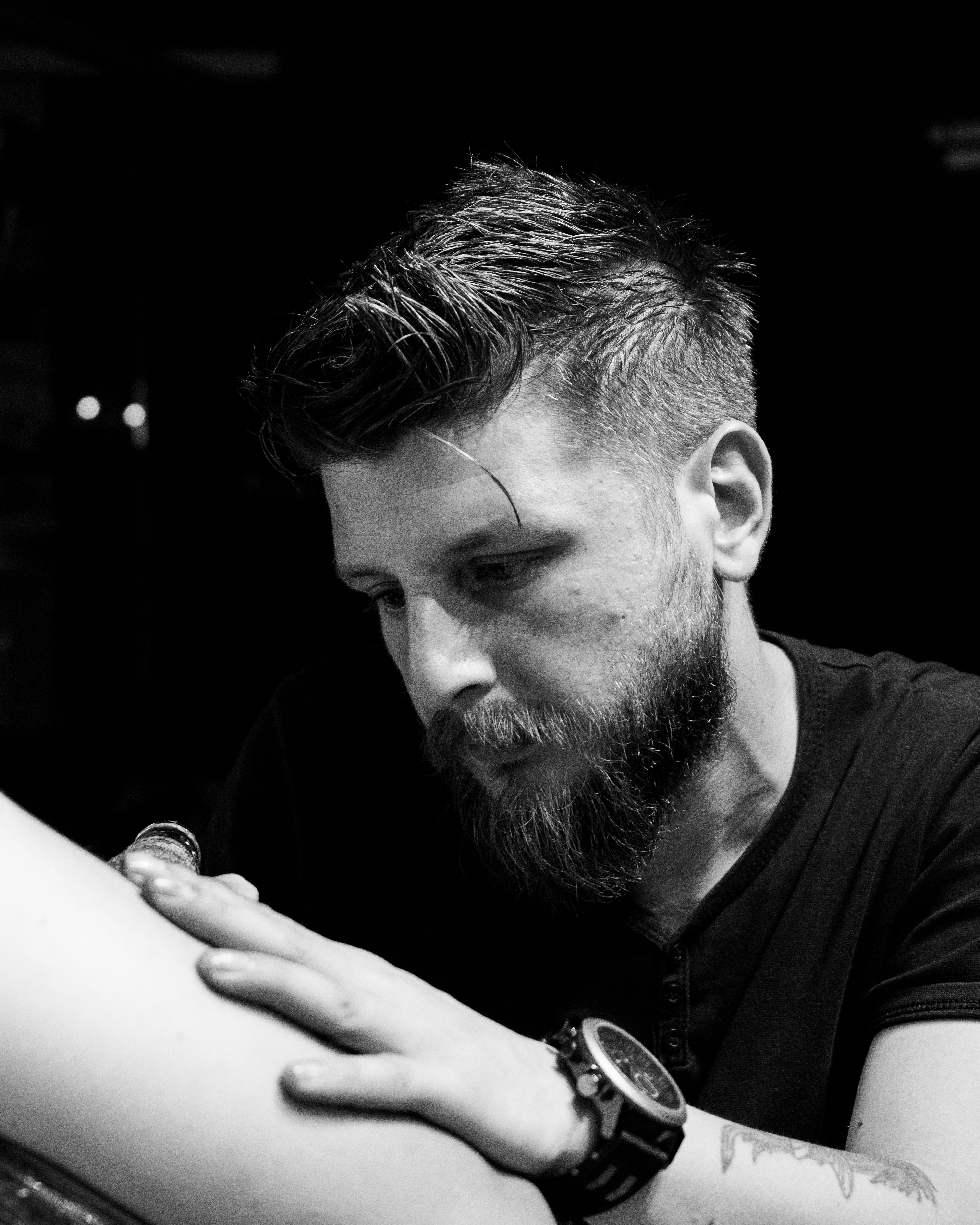A dedicated tattoo artist concentrating on his work in a professional studio setting.
