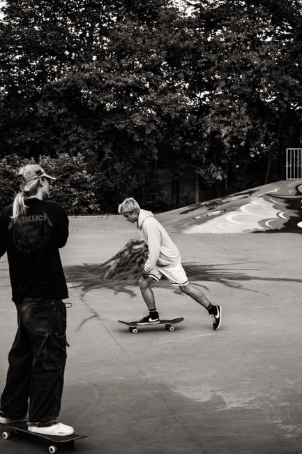 Two skateboarders enjoying a dynamic ride at an urban skate park in monochrome style.
