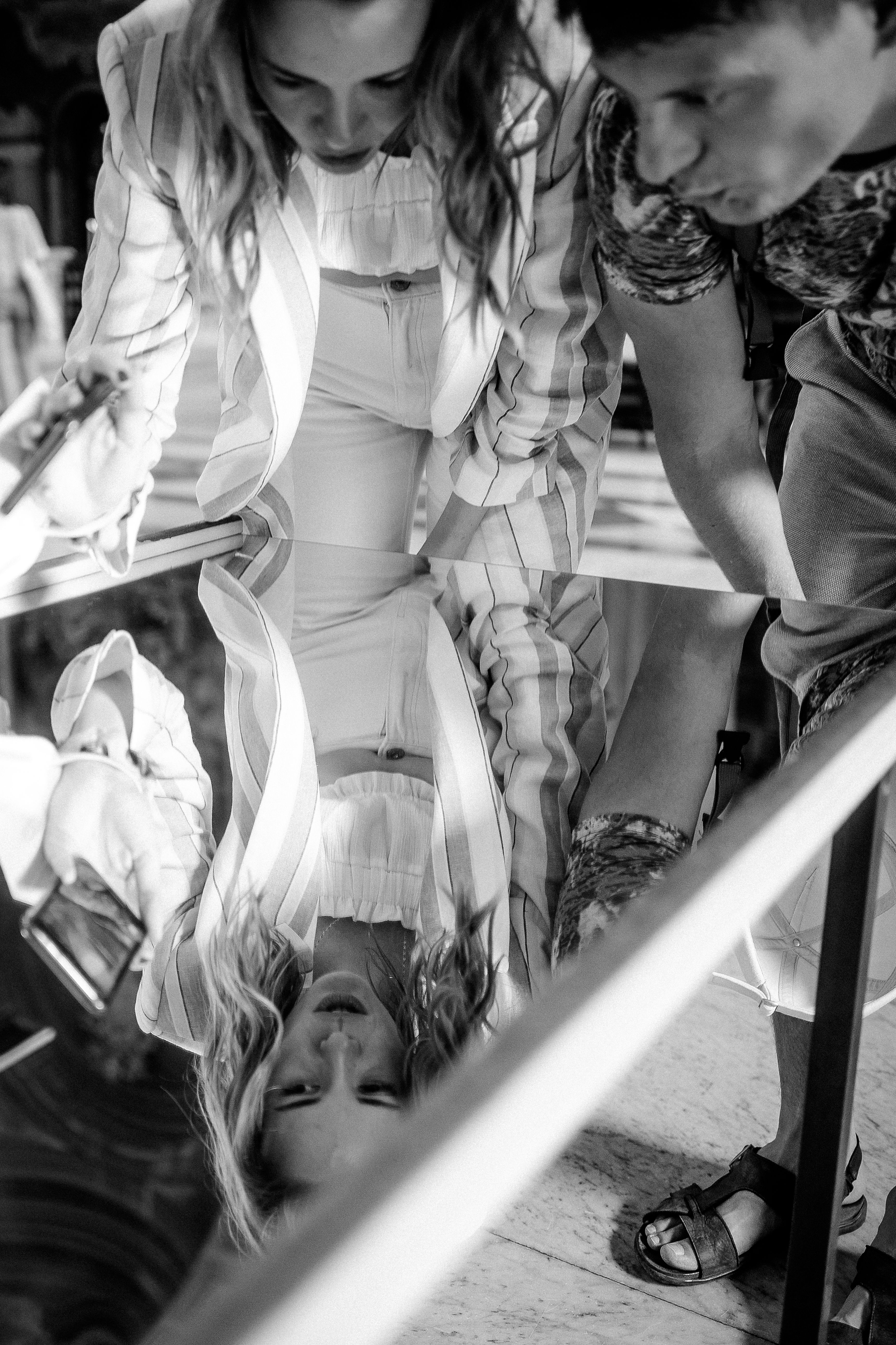 Black and white photo of a couple looking at their reflection in a mirror