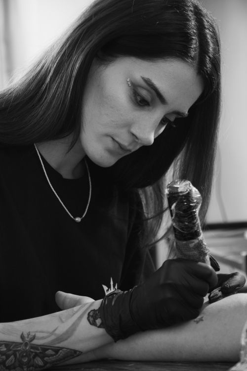Free A skilled tattoo artist carefully working on a design in a black and white setting. Stock Photo