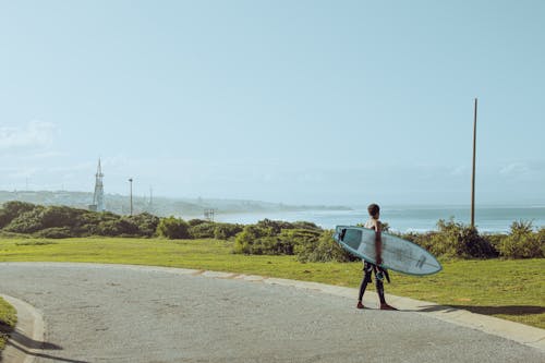 A Man Holding a Surfboard Walking near the Beach 