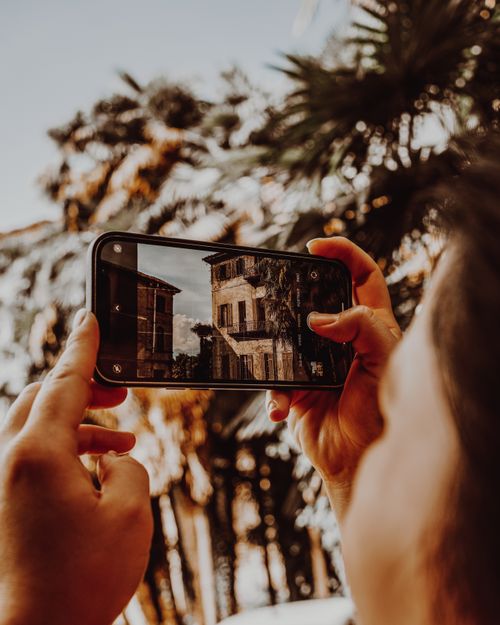 Free A person photographs historic Stresa building with smartphone, summer feel. Stock Photo