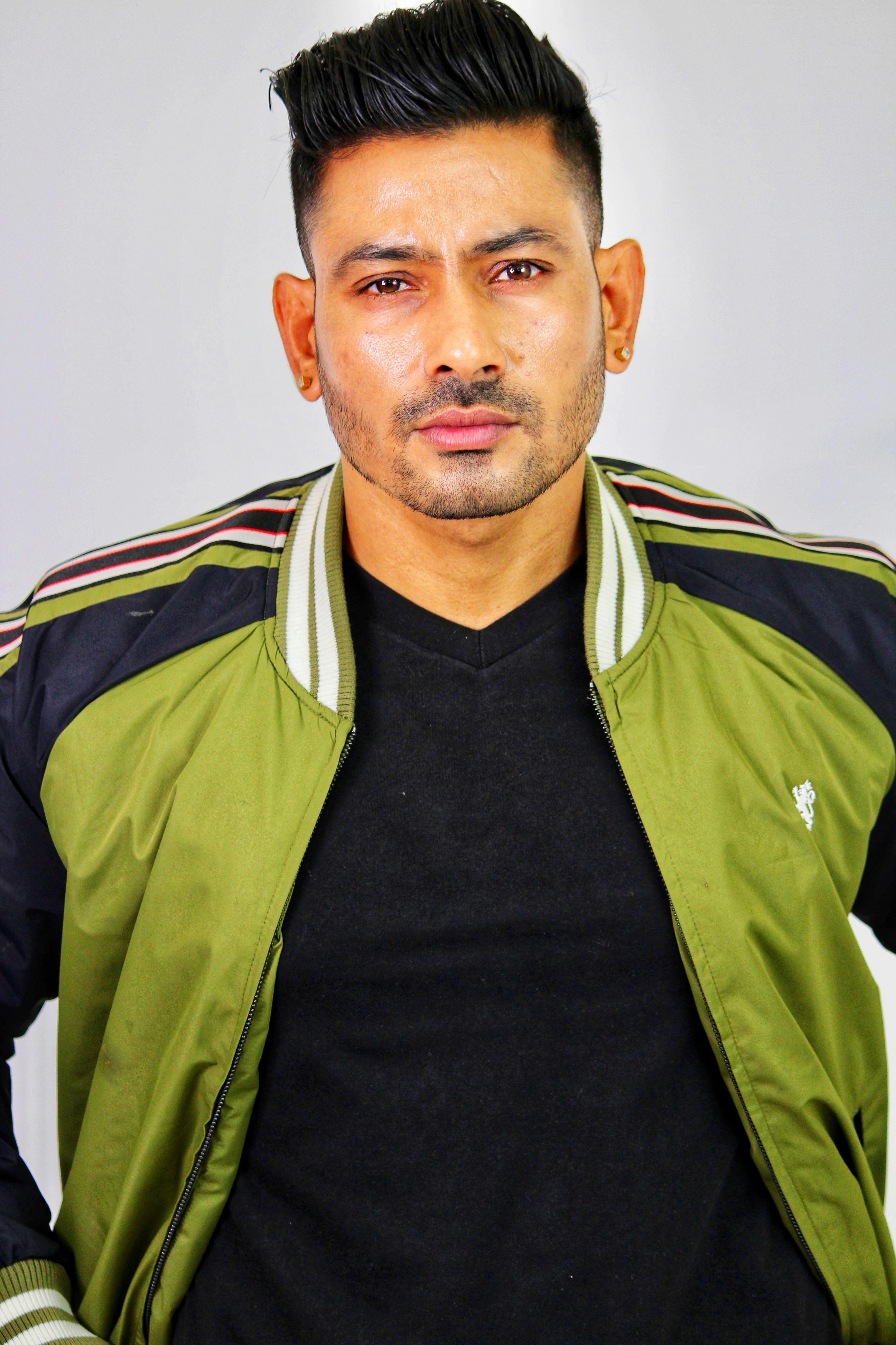 Portrait of a young man in a green sports jacket posing confidently in studio setting.
