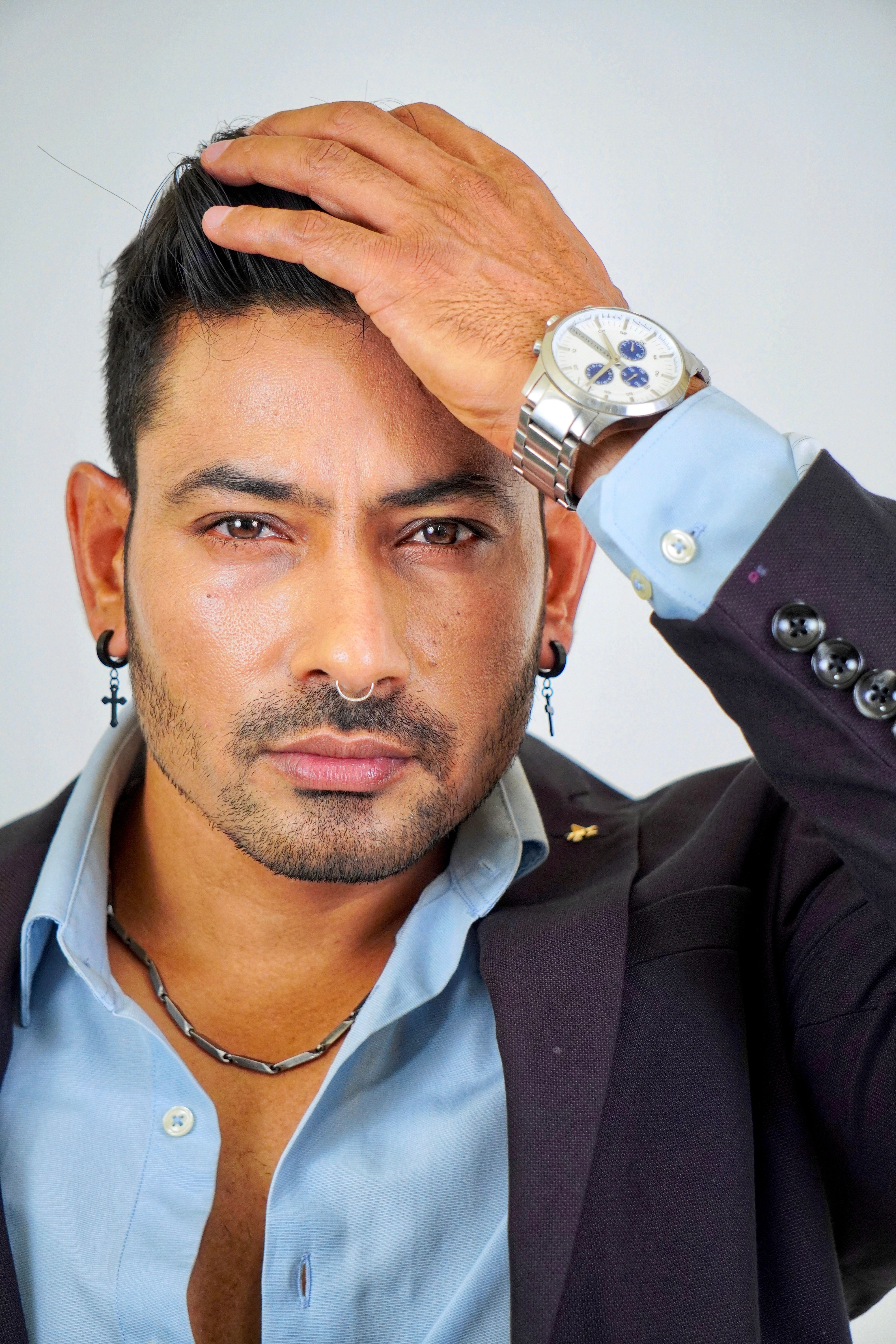 Confident man with facial hair and watch posing stylishly in studio.