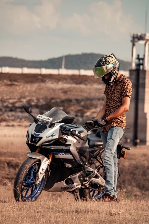 Free A man in a helmet stands by his stylish motorcycle in an open outdoor area. Stock Photo