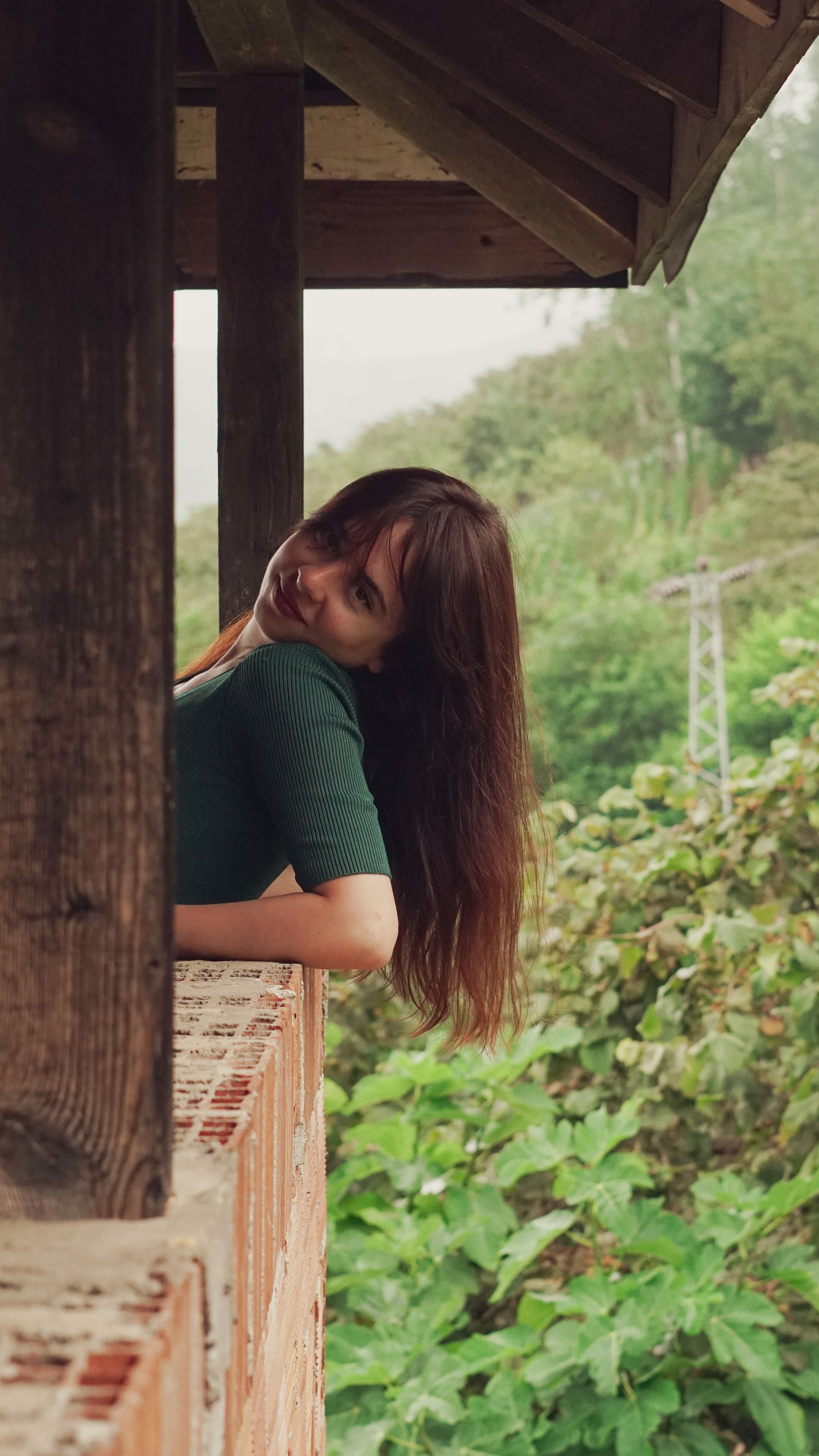 A woman leaning against a wooden railing · Free Stock Photo