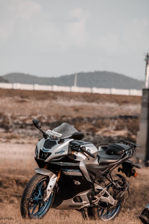Free A sleek sports motorcycle parked in a tranquil rural meadow with distant hills under a bright sky. Stock Photo