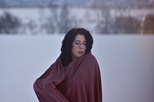 一位裹着披肩的女子在雪地背景前的冬季艺术肖像